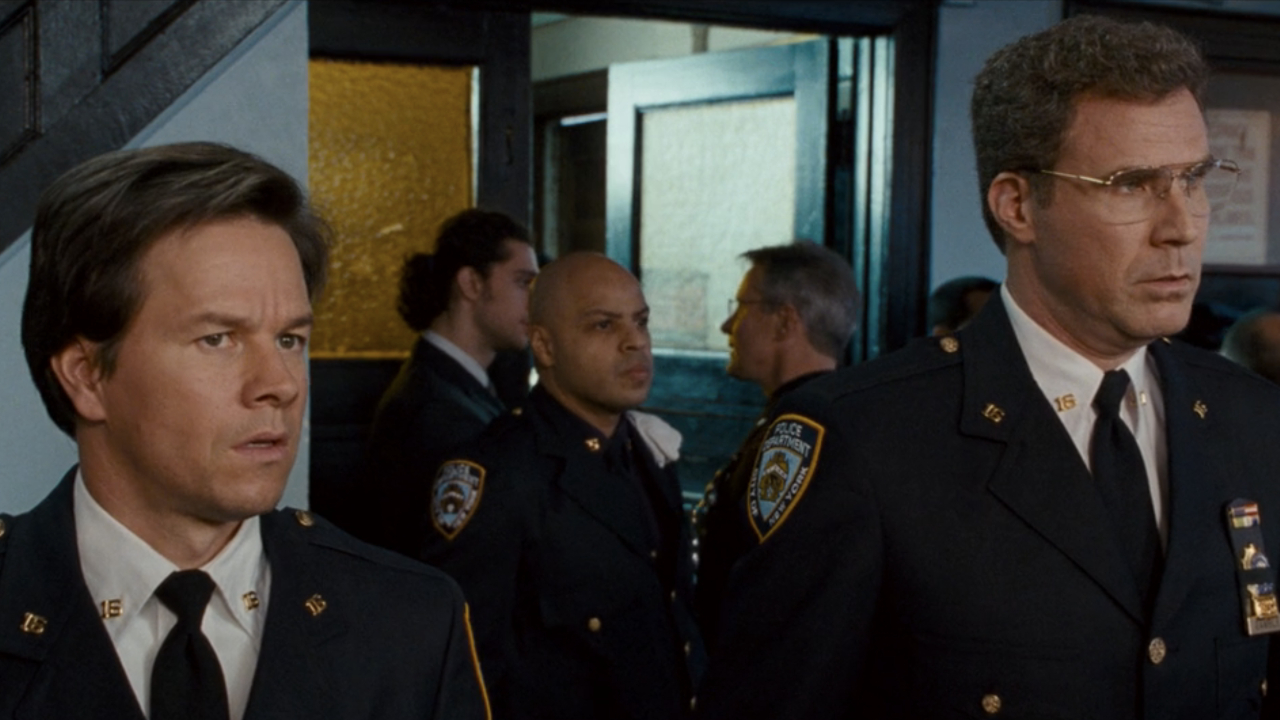 Mark Wahlberg and Will Ferrell stand in uniform looking slightly angry at a funeral in The Other Guys.
