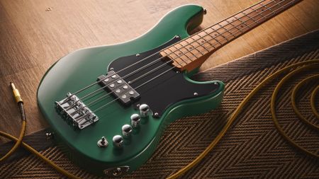 The Cort GB Short-scale Bass finished in green, photographed against a light wooden floor and rug.