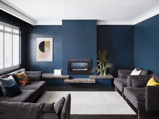 A living room with navy blue walls and dark gray sofa