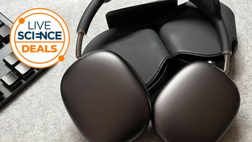 A space grey pair of Apple Airpods Max on a desk next to a PC keyboard