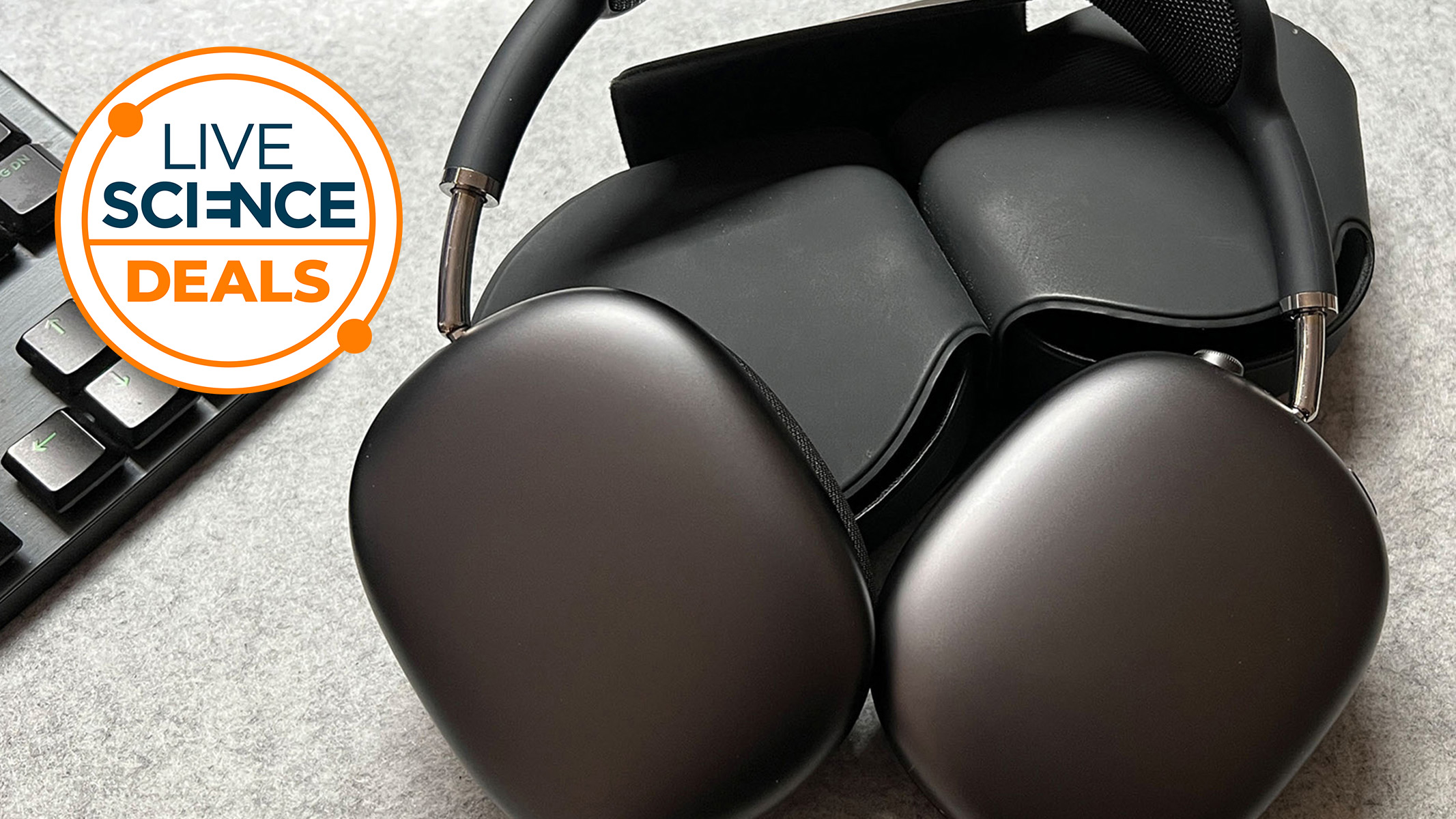 A space grey pair of Apple Airpods Max on a desk next to a PC keyboard