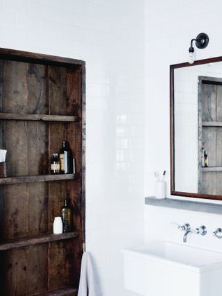 Reclaimed dark wood, open-shelving unit in white and bright bathroom scheme.