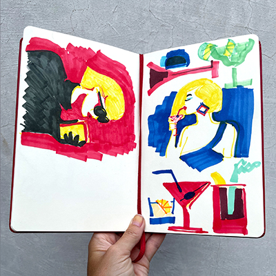 Marga holds one of her Moleskin sketchbooks in front of the camera. 