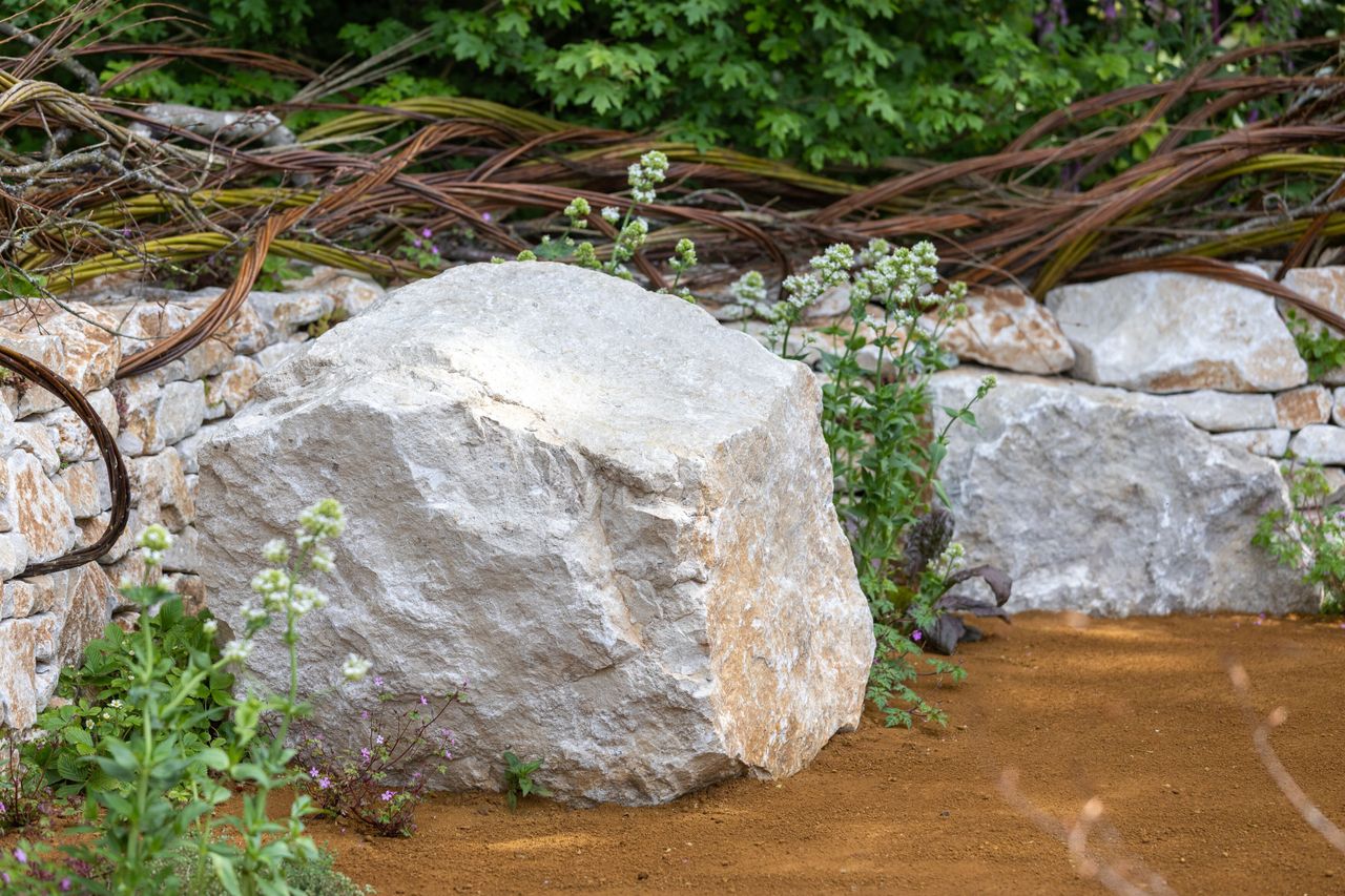 Images of the CPRE Show Garden On the Edge by Sarah Eberle. it focuses on grasses and flowers that grow around britain's edges, and is centred around a giant wooden carving of Gaia