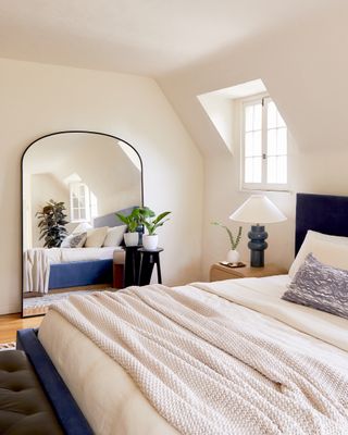 A bedroom with a mirror leaning against a wall