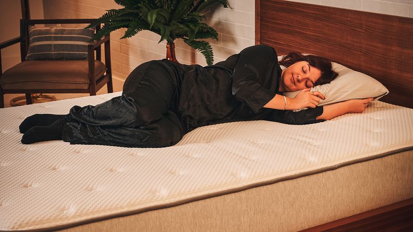A member of our sleep team lies on her side on the Nolah Original Mattress on a bed frame in a bedroom