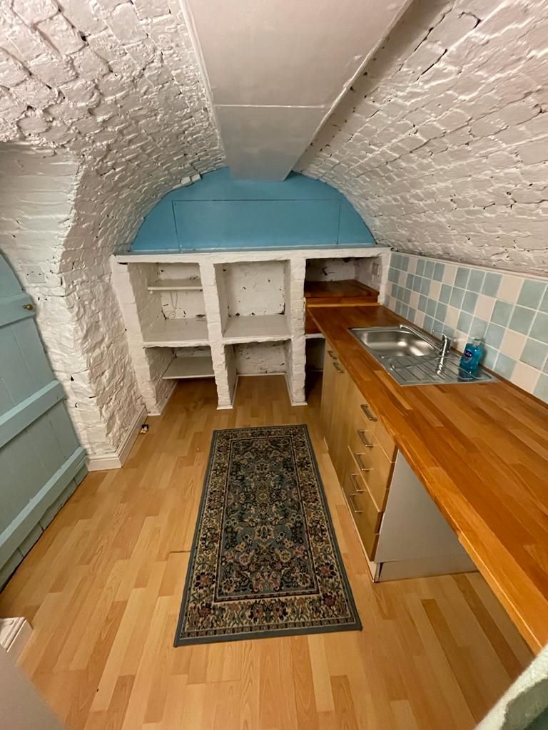 Cubby holes in the air raid shelter with a wooden worktop and metal sink to the right of the image