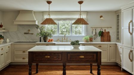Freestanding farmhouse kitchen table styled in a characterful kitchen with ivory cabinetry and woven rattan pendant lights hanging overhead