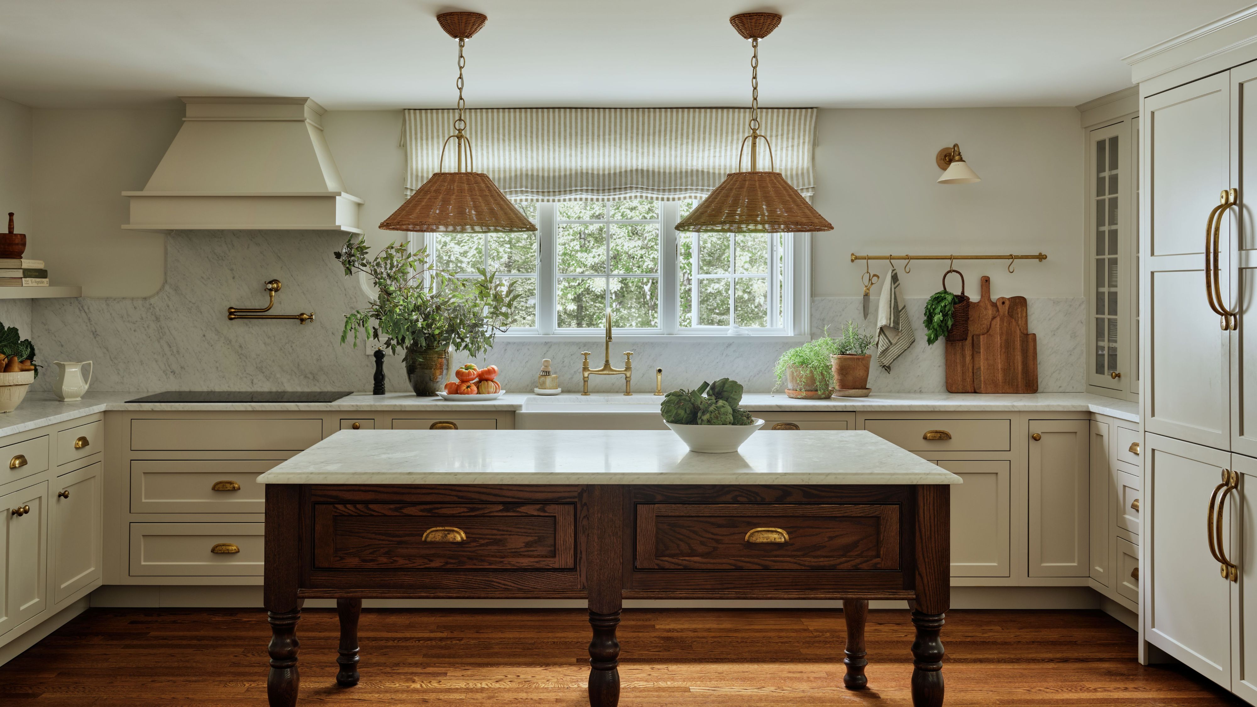 Freestanding farmhouse kitchen table styled in a characterful kitchen with ivory cabinetry and woven rattan pendant lights hanging overhead