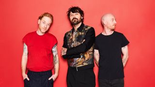 Biffy Clyro posing against a bright red background