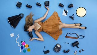 Professional photographer Vanessa Joy, lying on a blue floor surrounded by her camera equipment