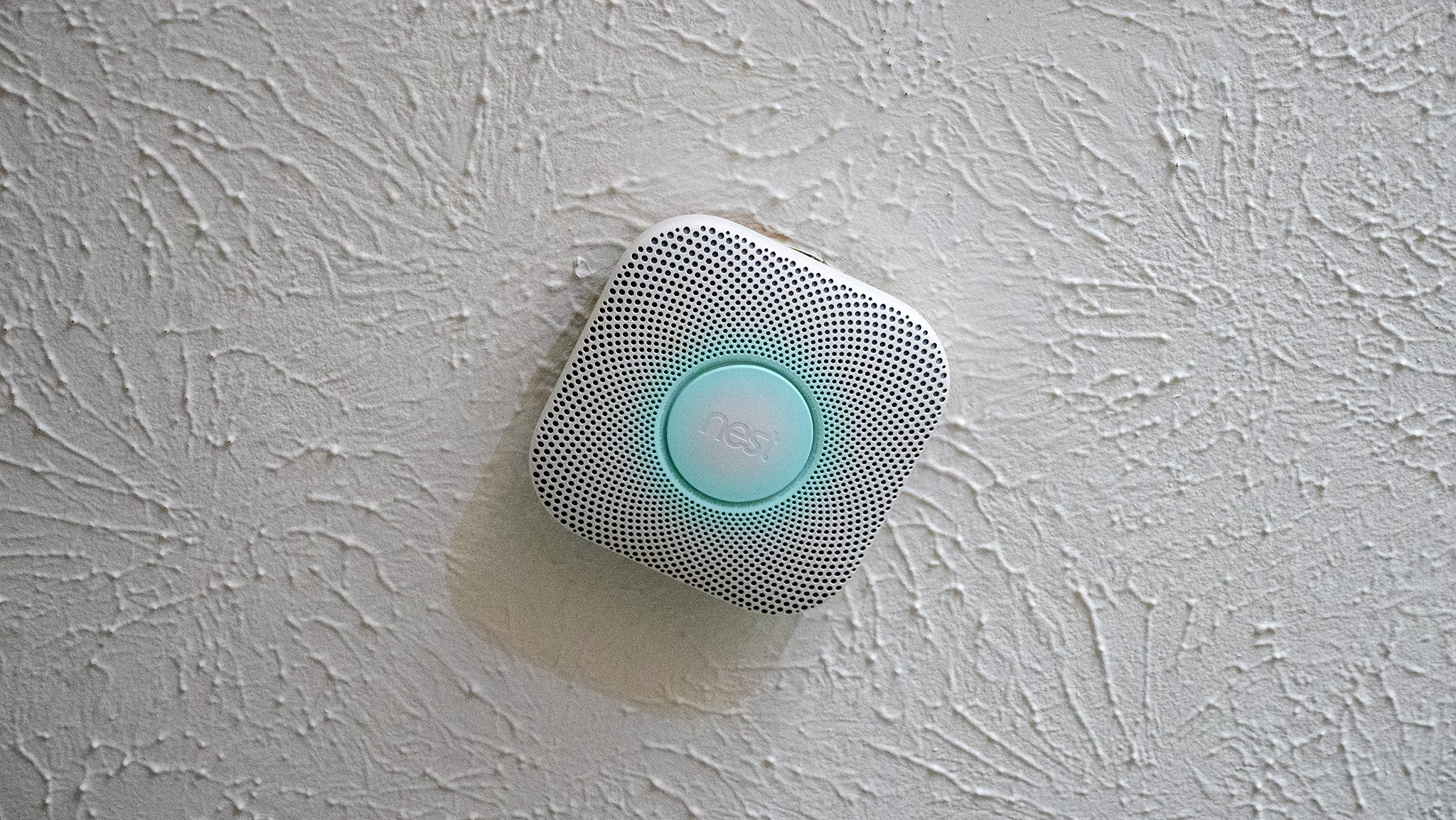 A Nest Protect illuminated in a dark hallway