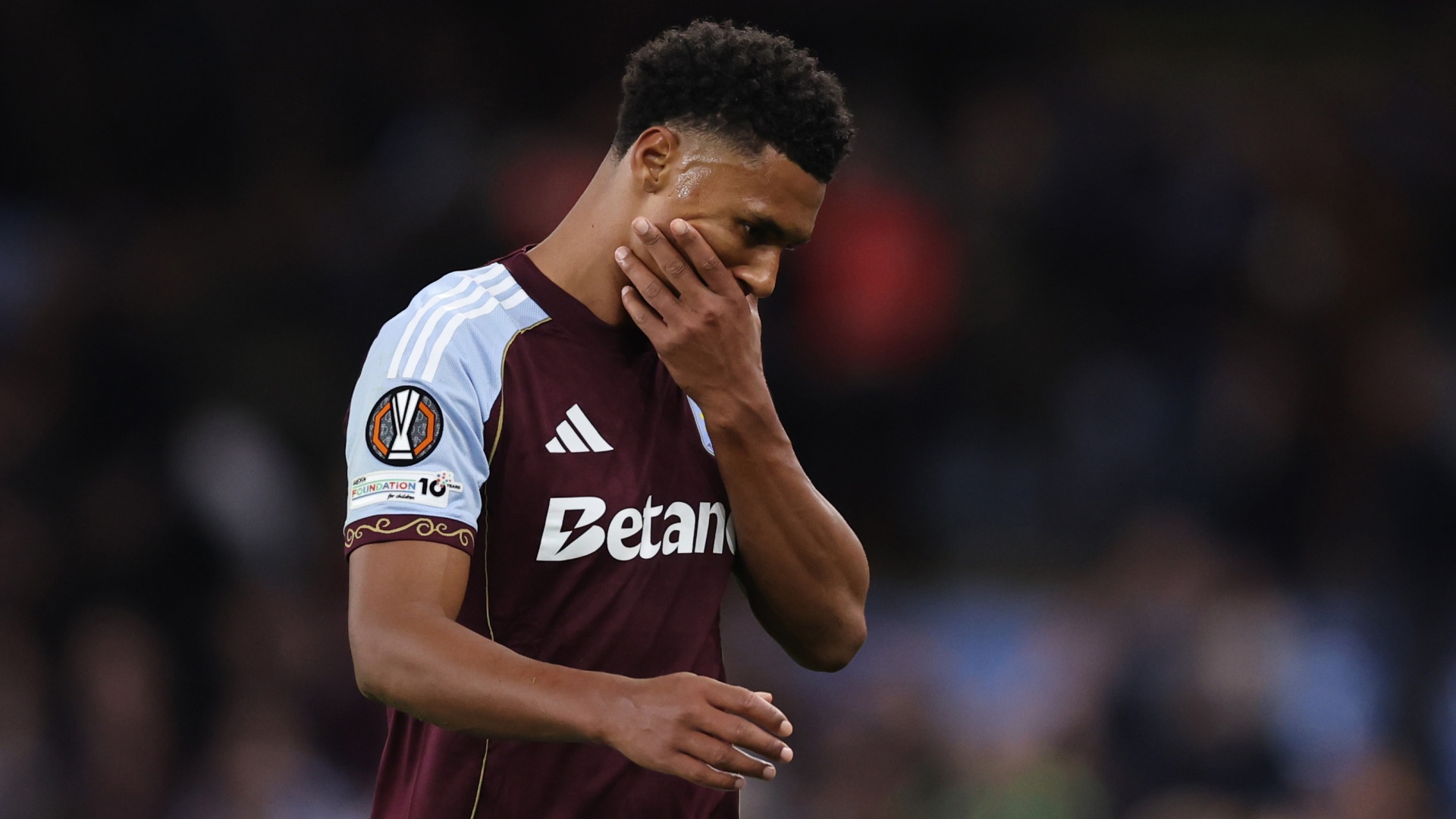 Aston Villa striker Ollie Watkins rubbing his face and staring at the ground