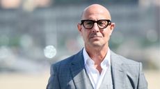 stanley tucci in a gray suit on a gray background