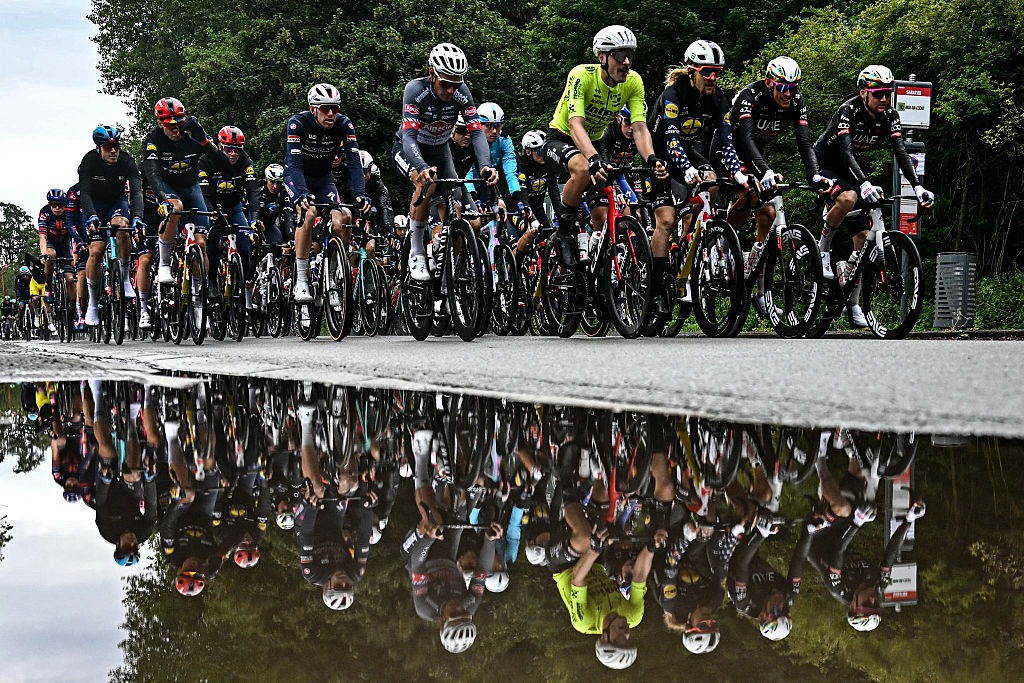 The pack of riders (peloton) is reflected in a puddle as they cycle shortly after the start of the 3rd stage of the 112th edition of the Tour de France cycling race, 178.3 km between Valenciennes and Dunkerque (Dunkirk), Northern France, on July 7, 2025. (Photo by Loic VENANCE / AFP) (Photo by LOIC VENANCE/AFP via Getty Images)