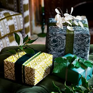 three Christmas presents wrapped in various of green wrapping paper with green ribbon