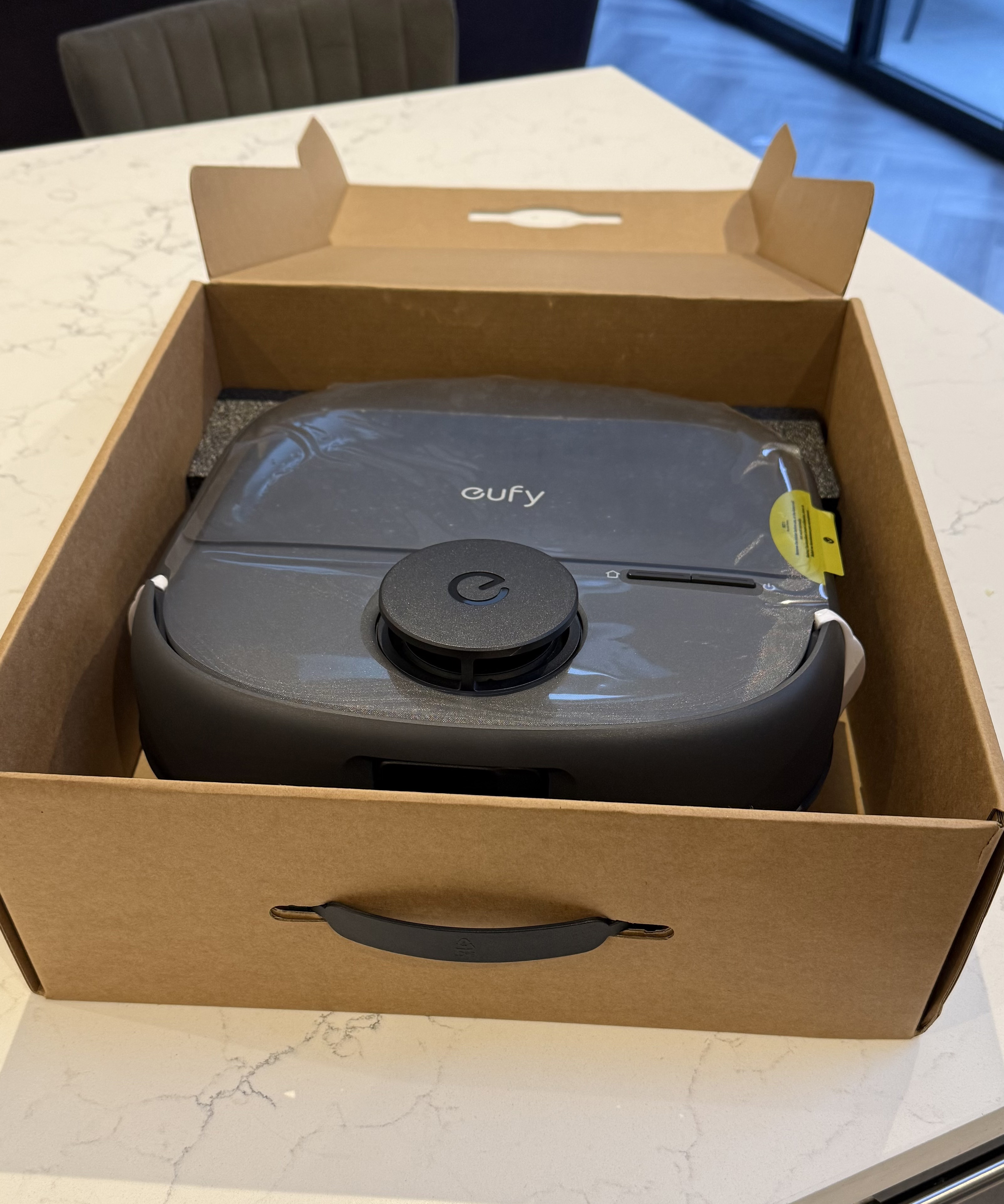 Eufy Omni C28 robot vacuum inside cardboard packaging with protective wrap