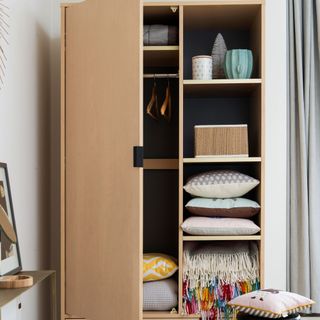 Wardrobe with shelving and hangers filled with cushions and throws