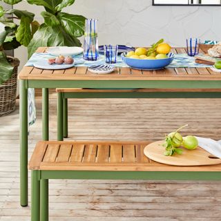 Wooden and green dining table set, blue tableware set, lemons, houseplant