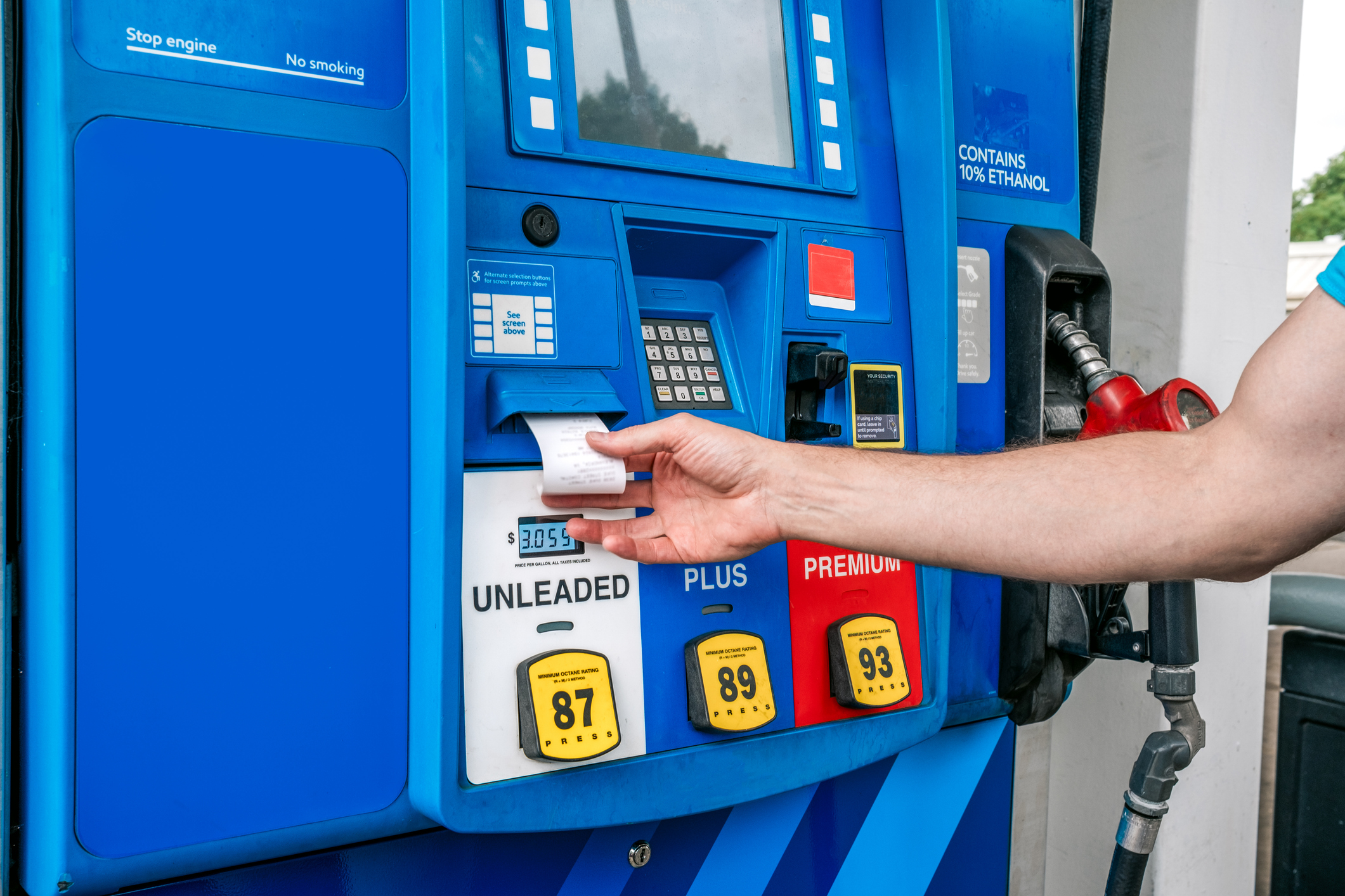 A man reaching for his receipt at a gas pump.