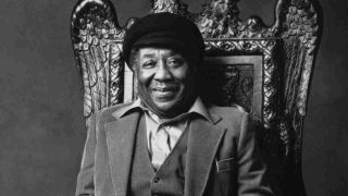 Muddy Waters posing for a photograph on a throne in 1978