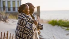 Black mature couple on the beach with blanket and coffee