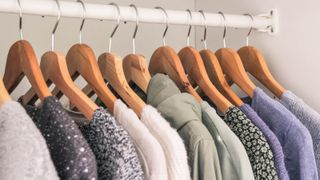 Clothes hanging from wooden hangers on a rail