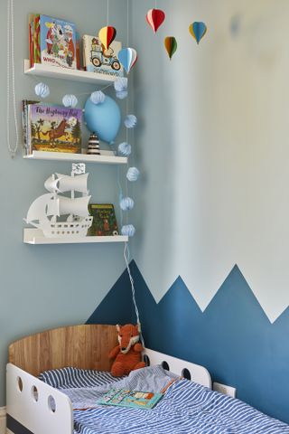 A corner of a child's bedroom with mountain-effect painted walls