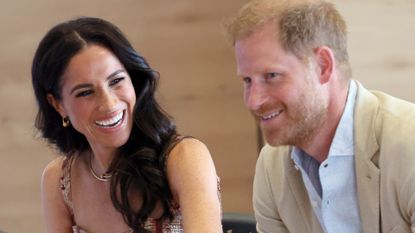 Meghan Markle laughs while wearing a pretty pink dress while looking at Prince Harry during their visit to Bogota, Colombia on August 15, 2024 