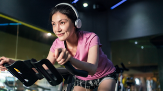 woman listening to music on exercise bike