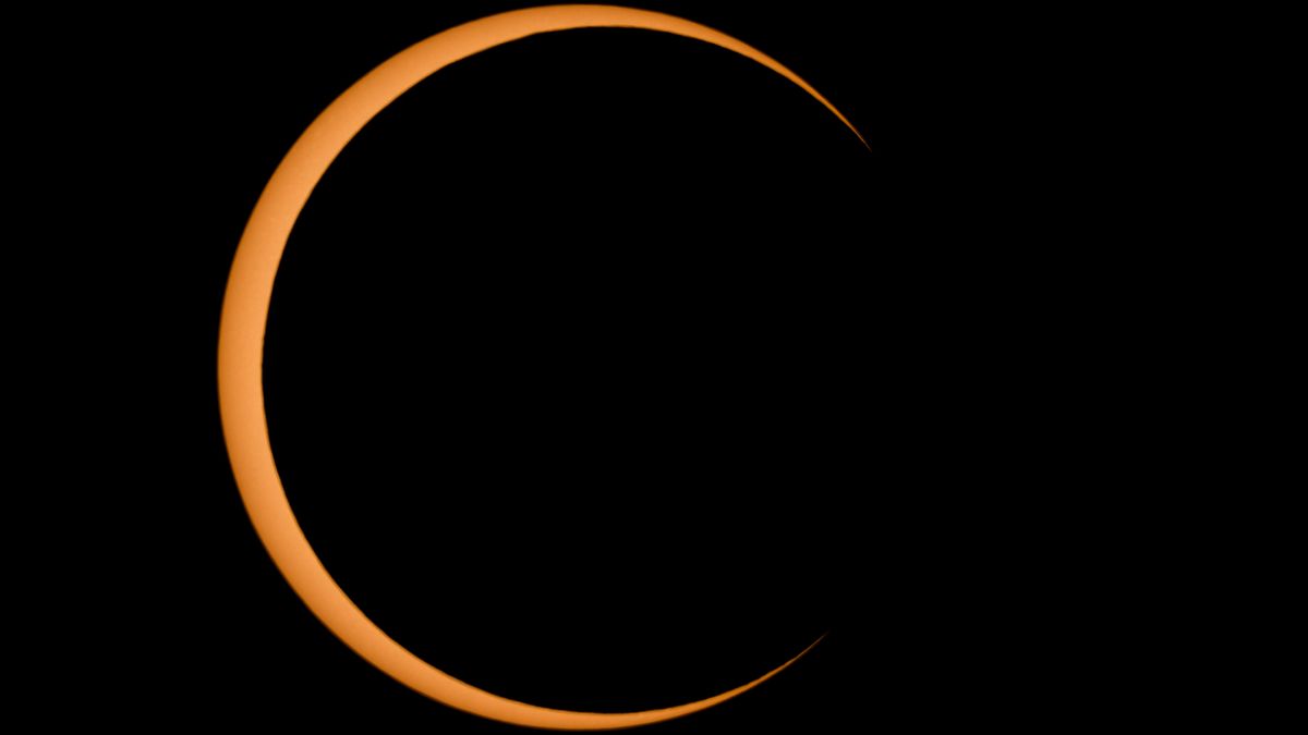 The moon blocks the sun's disk during a solar eclipse, leaving a thin crescent visible against a black sky.