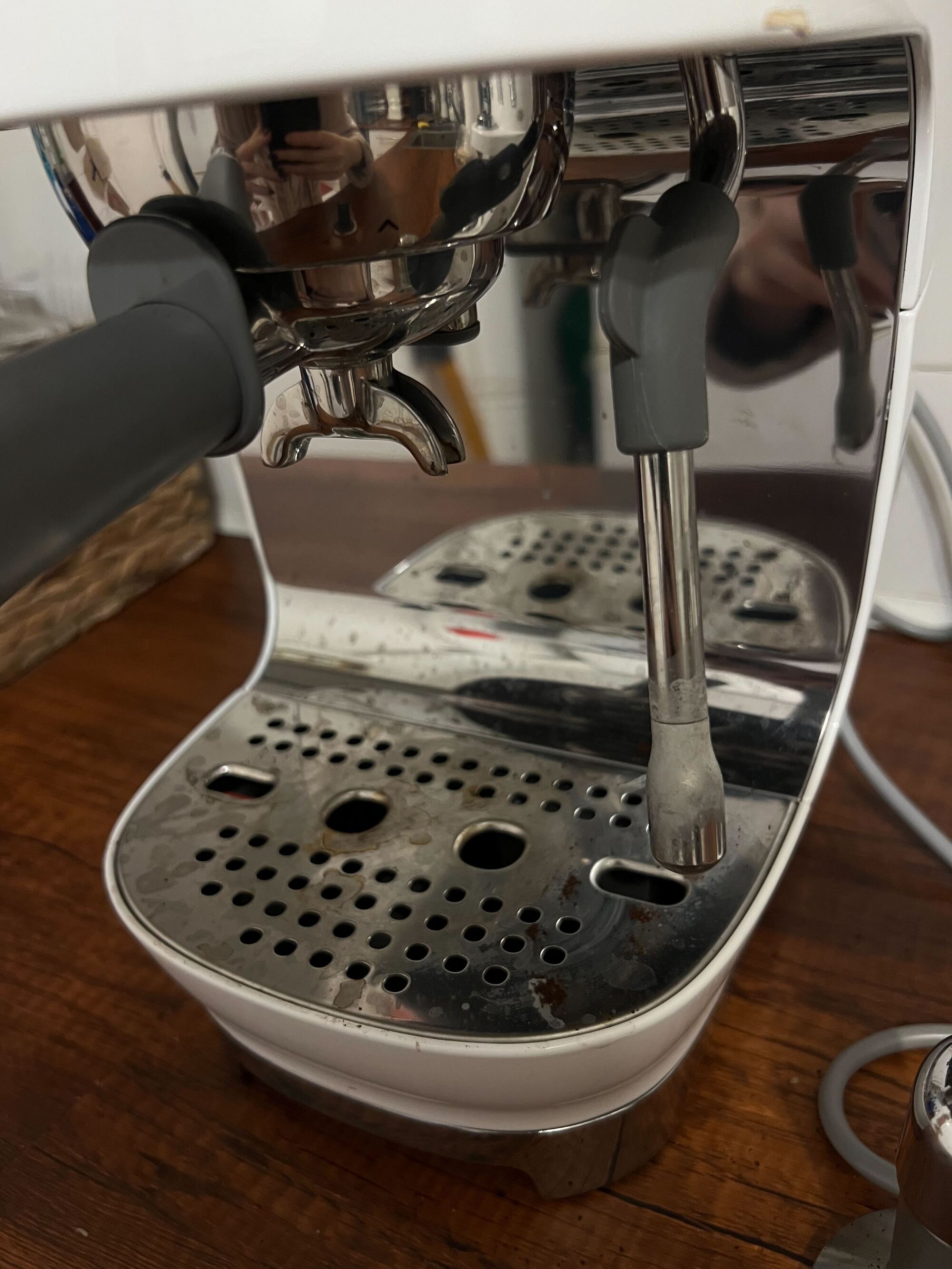 Image of a dirty milk steaming wand on a small, stainless steel coffee machine