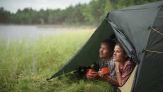 A couple lie in their tent and watch the rain