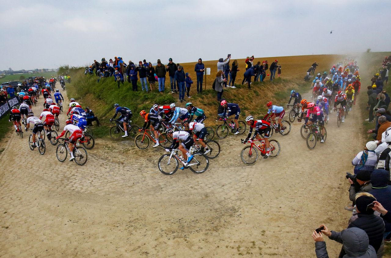 The peloton race through a cobbled section