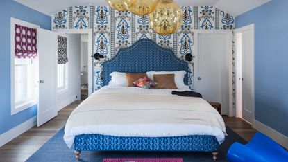 Blue bedroom with blue patterned wallpaper and statement bed