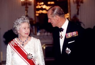 Queen Elizabeth wears a white dress and her sapphire earrings and necklace