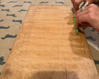 Scraping a chopping board with a green knife