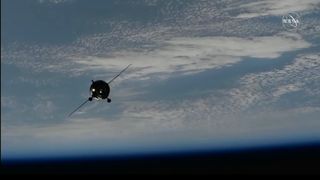 A spacecraft approaches with earth and the blackness of space in the background.