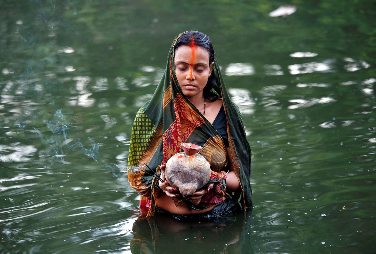 A Hindu devotee holds offerings as she worships the Sun God in the waters of a pond during the religious festival of Chhat Puja in Kolkata, India.