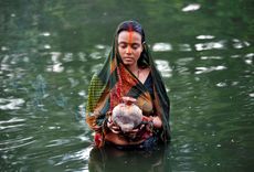 A Hindu devotee holds offerings as she worships the Sun God in the waters of a pond during the religious festival of Chhat Puja in Kolkata, India.