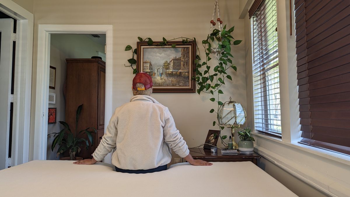 Our tester Alex sitting on the edge of the Essentia Stratami Organic mattress