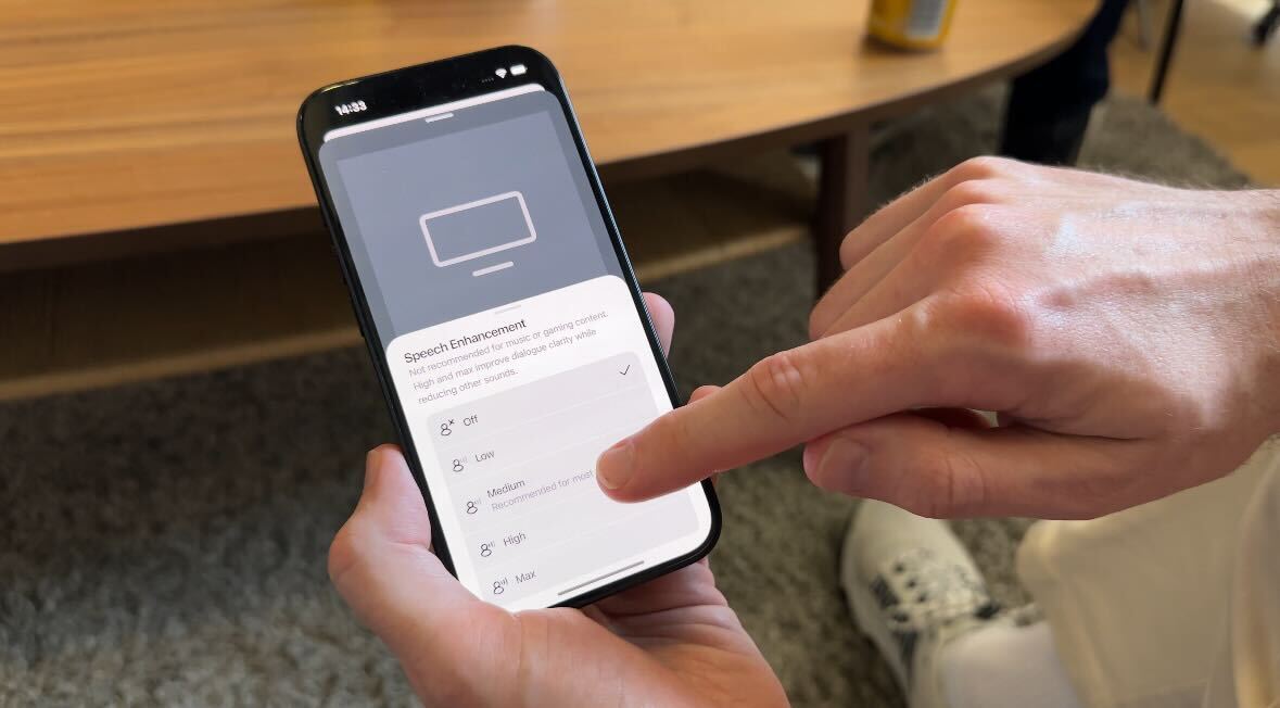 A man holding a phone with Sonos' new AI Speech Enhancement features shown on the screen