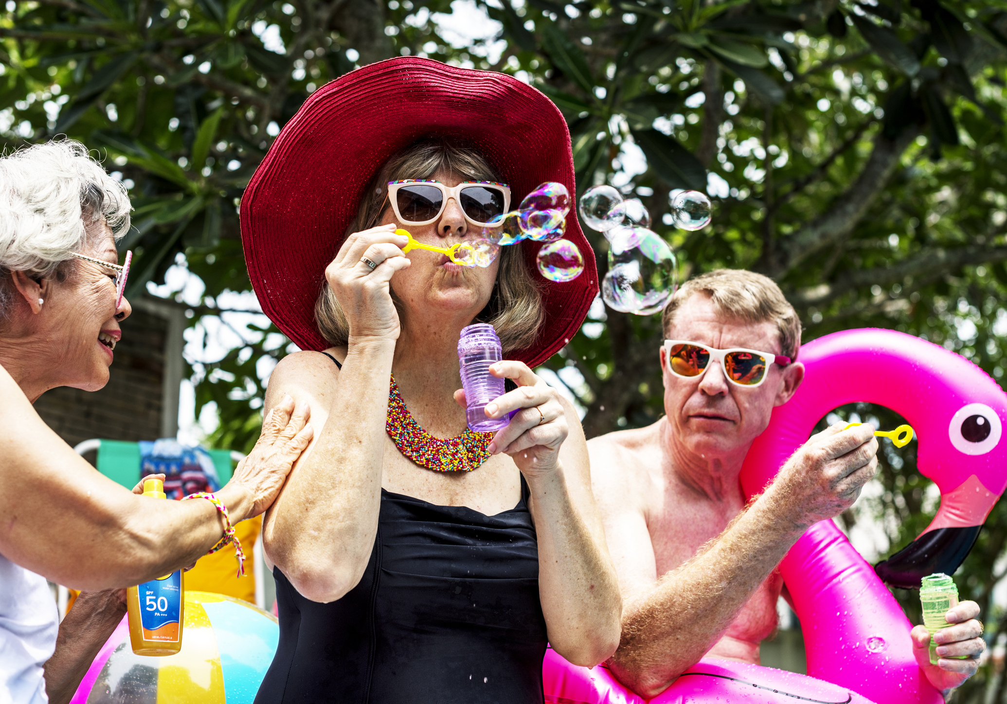Older adults blowing bubbles by a pool