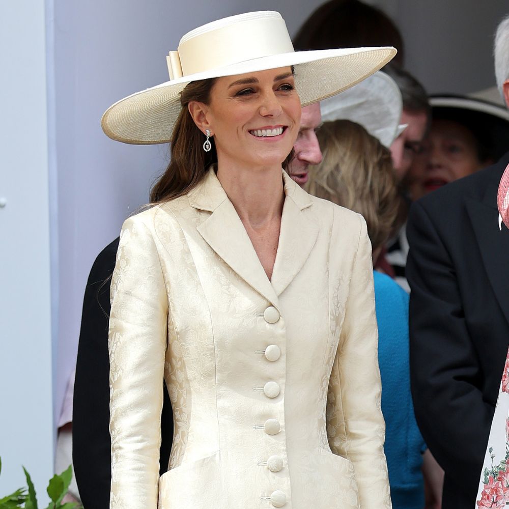 Kate Middleton wears a butter yellow coat dress with beige heels and a yellow wide-brim hat.
