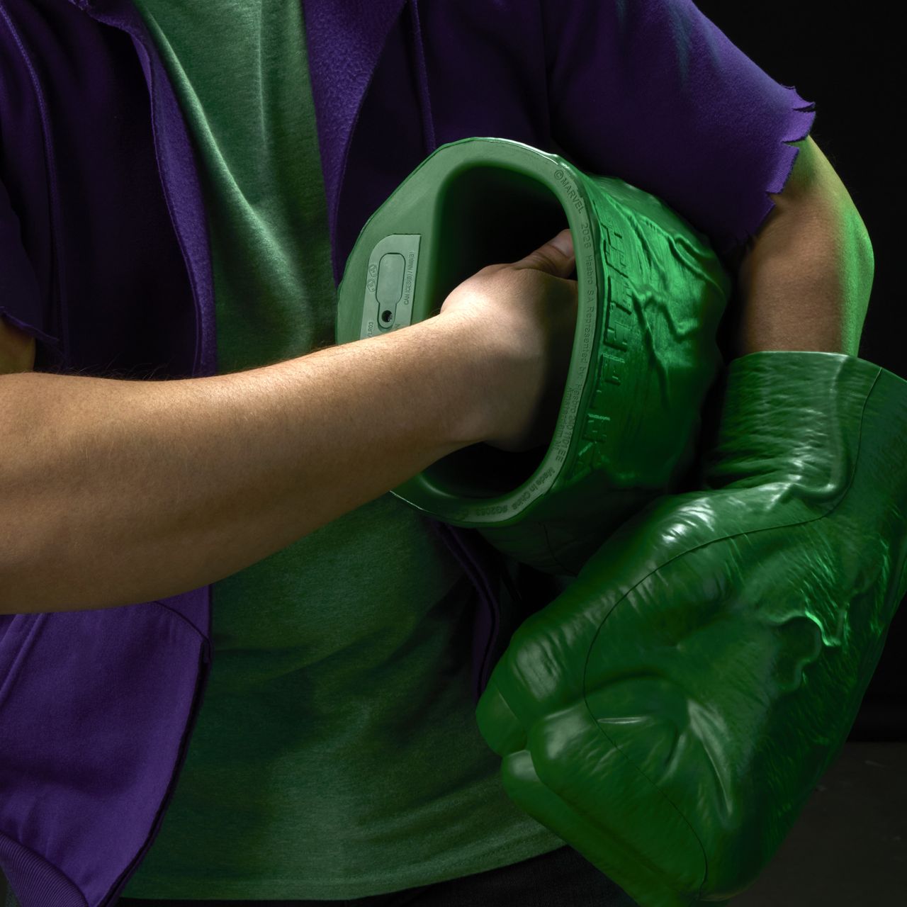 A roaring man with two Hulk Fists pretends to punch with them against a black background