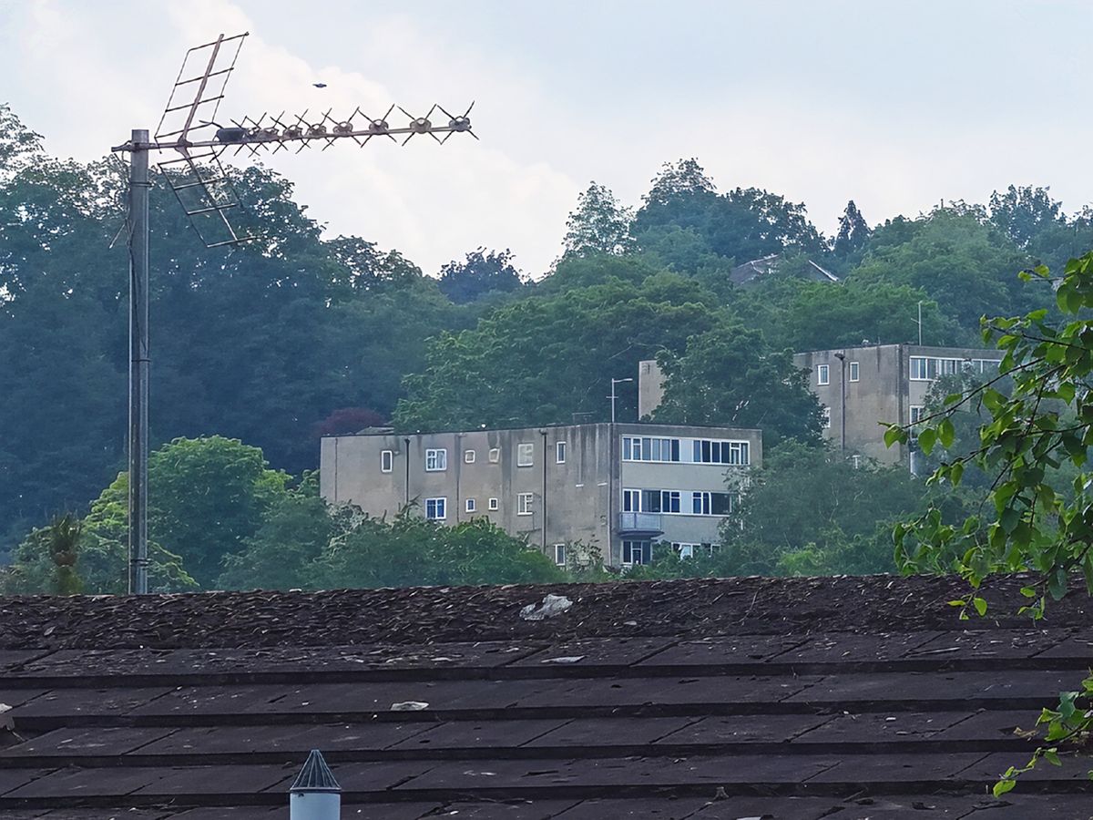 A massively zoomed in digital image of buildings and a rooftop with the details significantly sharpened.