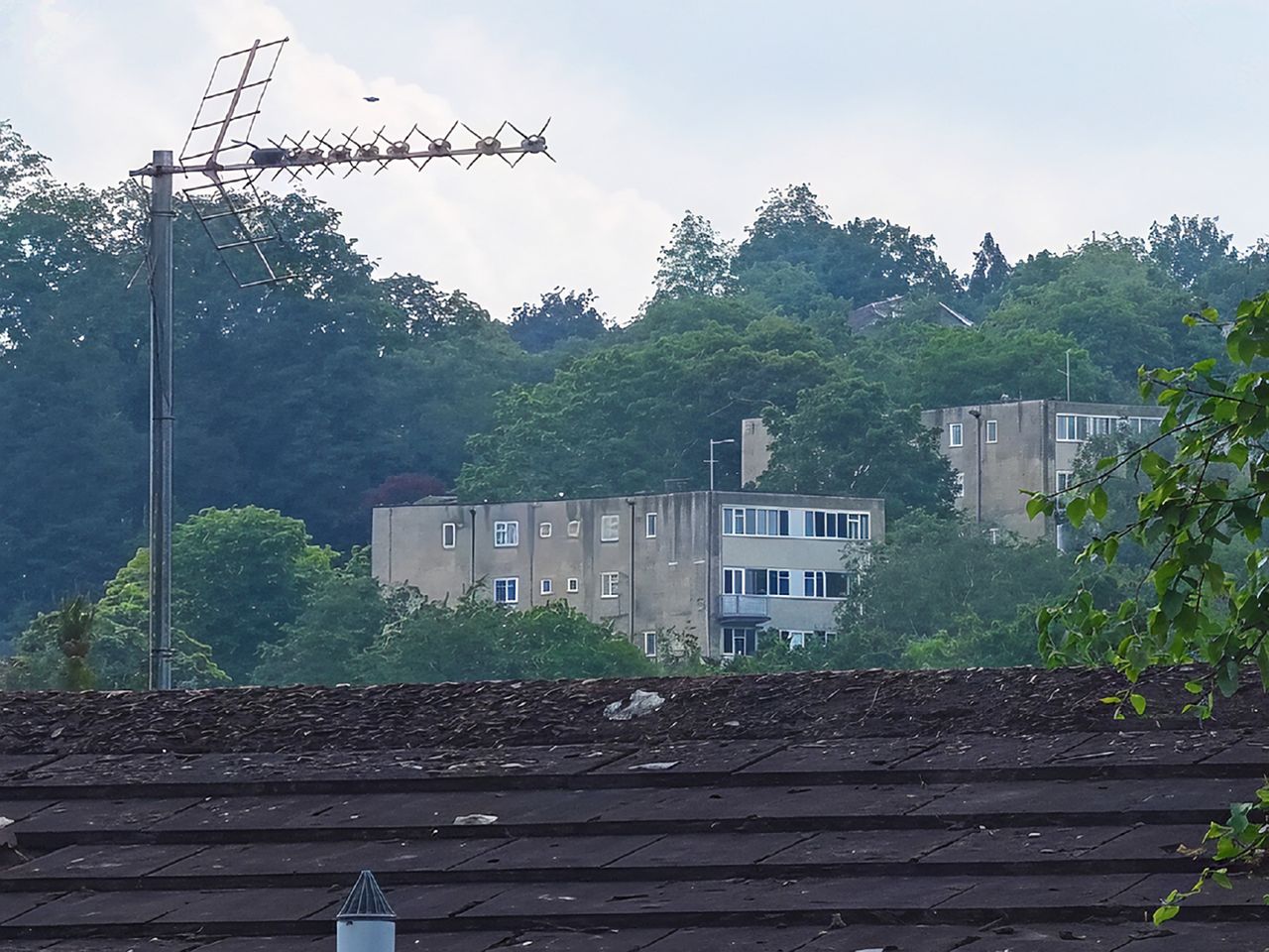 A massively zoomed in digital image of buildings and a rooftop with the details significantly sharpened.