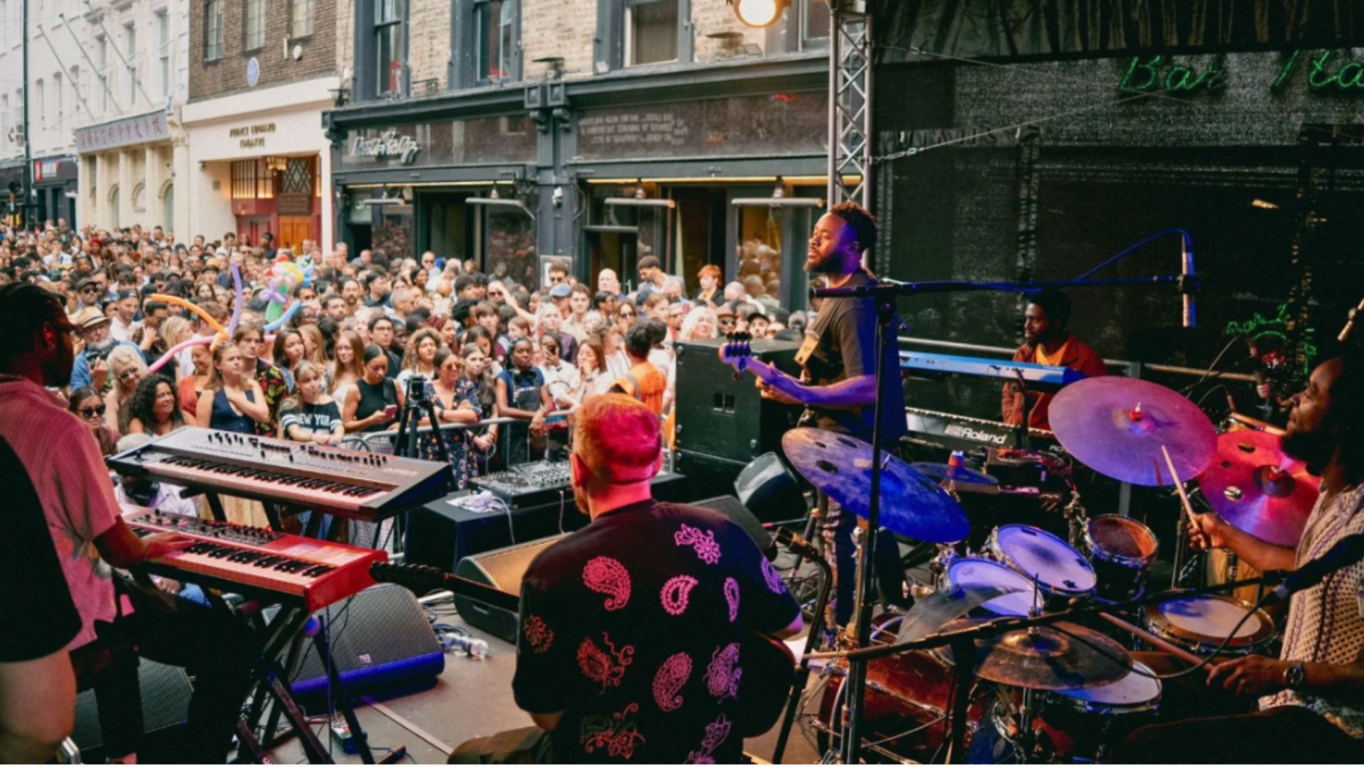 an image of the street party in a previous year, with the shot taken from the back of the stage, showing a band performing in front of a crowd