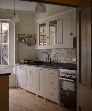 Grey tiled splashback,, white wooden base cabinets, black countertop