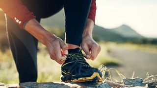 A runner tying their shoelace on the trail